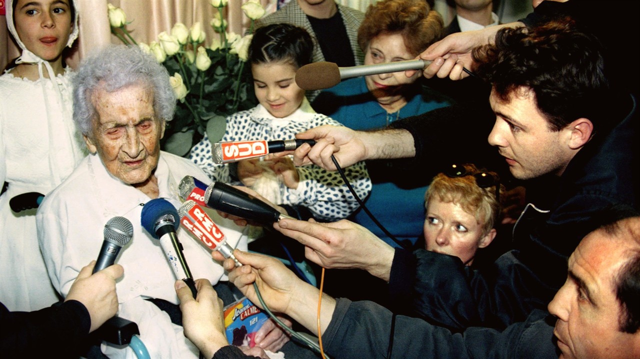 An elderly woman interviewed by many reporters